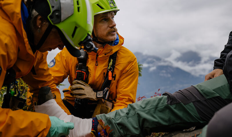 two men tending to a leg on a mountain